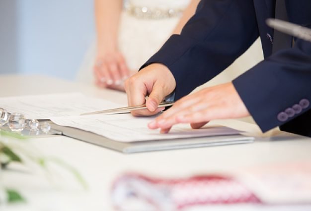 Groom hand with a pen signing wedding contract